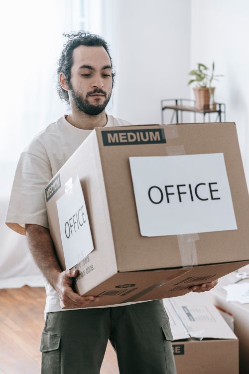 Mann traegt Umzugskarton mit der Aufschrift Office