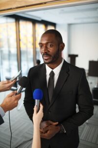 Politiker wird bei einer Pressekonferenz von mehreren Mikrofonen interviewt